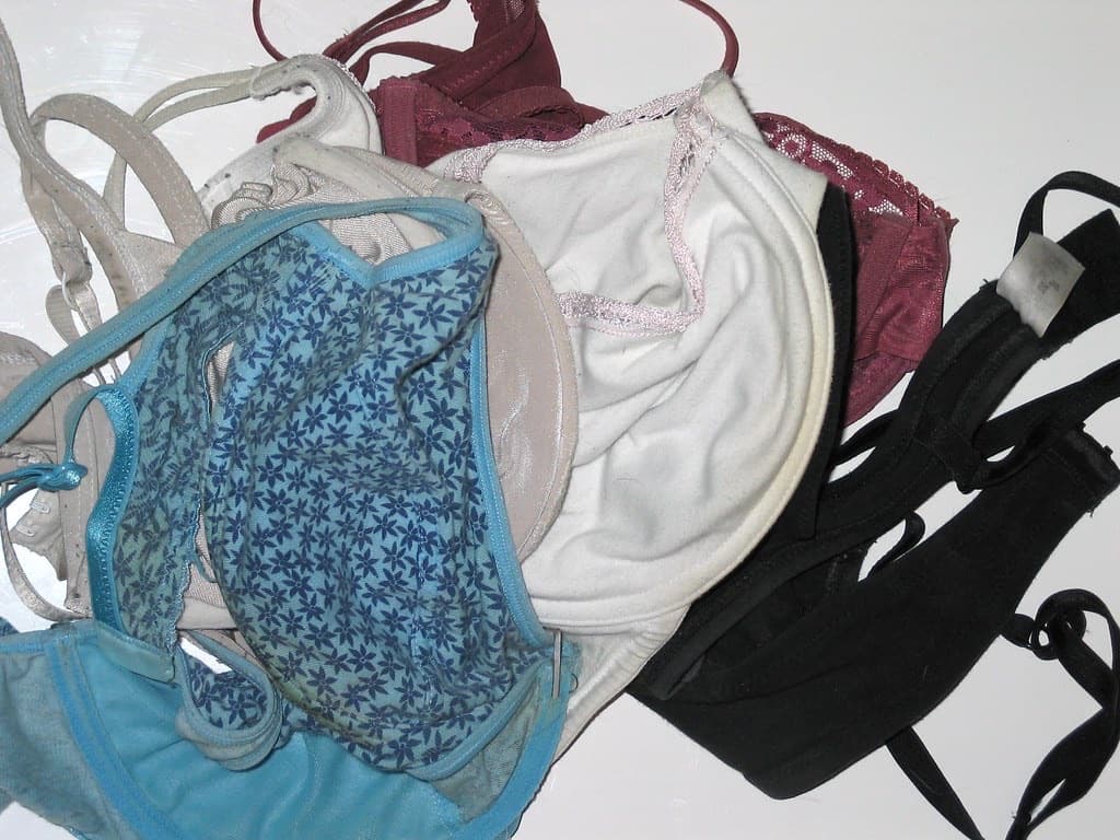 A pile of old, worn-out bras in different colors