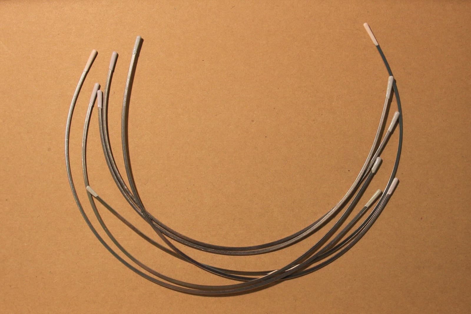 Three pairs of bra underwires laid on kraft paper