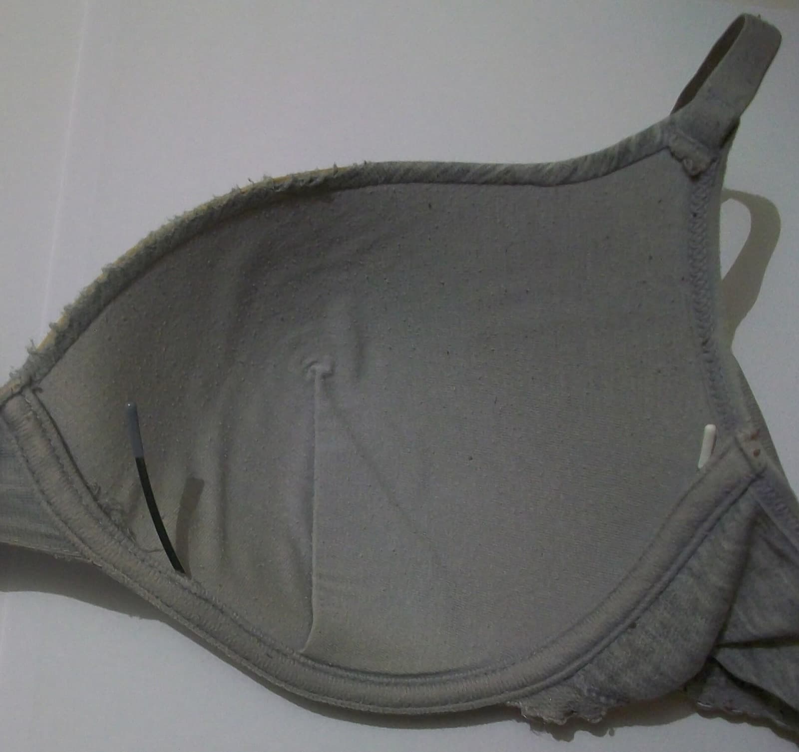 Worn-out bra with the metal underwire poking through the frayed casing